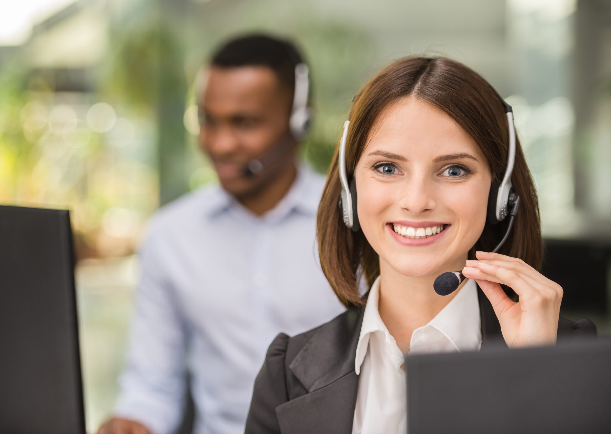 Beautiful young lady talking on headset at call center office.